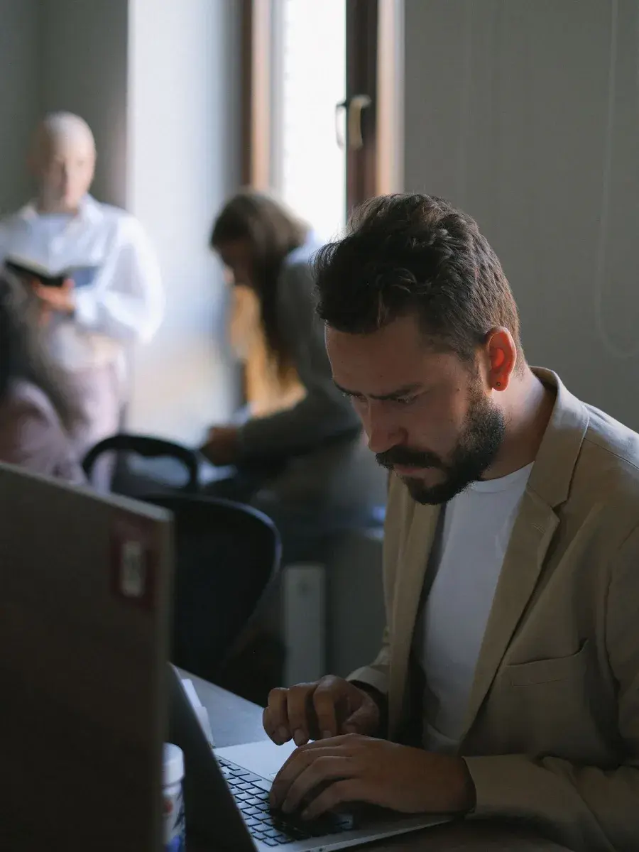 Rad na laptopu u kancelariji sa timom u pozadini